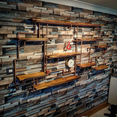 Steampunk industrial shelving unit with copper pipes, wood shelves, and vintage gauges on a rustic wall.