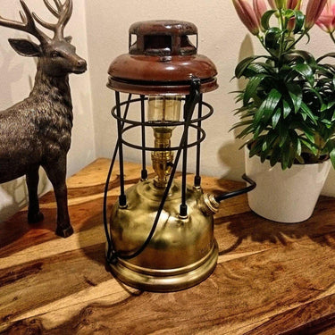 Vintage brass and iron steampunk table lamp on wood surface with deer figurine and potted plant