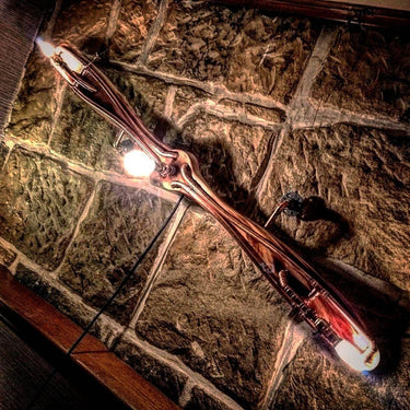 Wall-mounted steampunk propeller light fixture with exposed bulbs on rustic stone wall