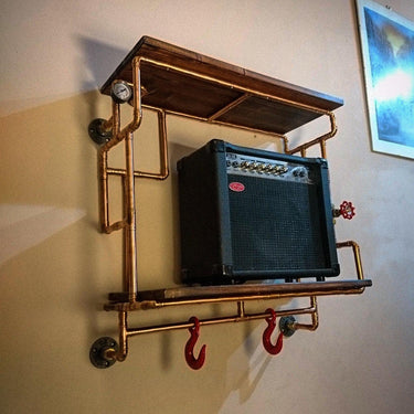 Steampunk shelving unit with copper pipes, wood shelves, red hooks, and industrial details wall mounted.