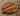 Thick round walnut wood chopping board with rich grain on a textured surface
