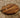 Thick round walnut chopping board with oil bottle on carpeted surface