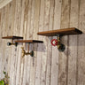 Steampunk wall shelves with industrial pipe fittings and wood tops on rustic wood panel wall
