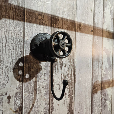 Industrial steampunk coat hook with valve detail on rustic wooden wall