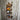 Industrial copper pipe wall-mounted wine rack holding four bottles on rustic wood panel wall