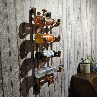 Handmade steampunk copper pipe wall wine rack holding bottles, mounted on rustic wood panel