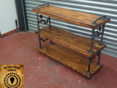 Industrial style vintage shelving unit with dark wood shelves and metal pipe frame in workshop