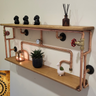 Handmade industrial pipe shelf with wooden planks, copper pipes, and steampunk decor.
