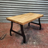 Industrial steampunk coffee table with solid wood top and black metal legs on workshop floor