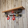 Steampunk industrial wall shelf with wood plank, metal pipes, red hooks, and gauge decor