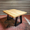 Industrial steampunk coffee table with solid wood top and black metal legs, on concrete floor