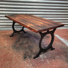Industrial steampunk coffee table with dark wood top and black metal legs in workshop setting.