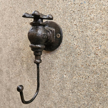 Industrial steampunk metal wall hook with vintage valve design on textured wall