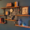 Industrial steampunk wall shelf with wooden planks, pipes, books, decor and vintage art.