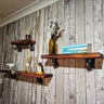 Handmade industrial pipe wall shelves with wooden planks on rustic wood panel wall