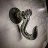 Industrial metal coat hook with exposed bolts mounted on a concrete wall