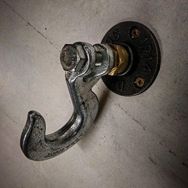 Industrial coat hook with metal and pipe fittings, mounted on concrete wall