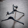 Industrial pipe wall-mounted clothes hanger rail with two black hangers on textured wall