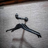 Industrial pipe wall clothes hanger rail with black hangers on textured wall