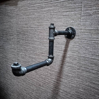 Industrial pipe clothes hanger rail mounted on a textured wall, steampunk decor style