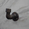 Industrial rustic coat hook made from black metal pipe on a marble wall