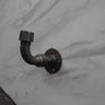 Industrial rustic coat hook made from metal pipe on marble-effect wall