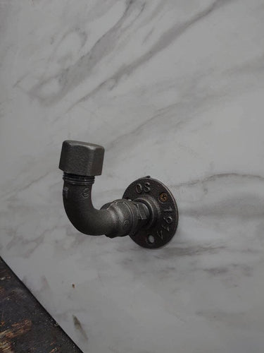 Industrial rustic coat hook made from metal pipe on a marble wall