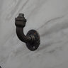 industrial steampunk coat hook made from black pipe, mounted on a marble wall