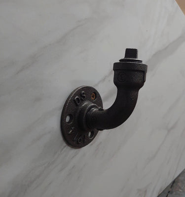 Industrial steampunk wall-mounted coat hook made from black iron pipe on white marble wall