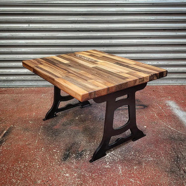 Steampunk industrial coffee table with iron legs and rectangular wood top on workshop floor