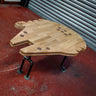 Industrial wood coffee table shaped like a spaceship with metal pipe legs on a red floor.