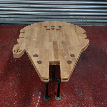 Handmade wooden coffee table shaped like a spaceship with industrial metal pipe legs.