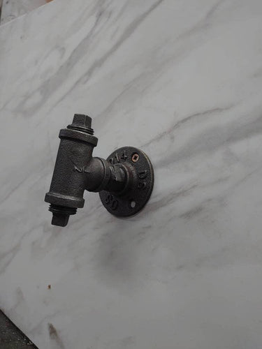 Retro industrial metal pipe coat hook on marble wall