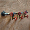 Industrial steampunk coat hooks made from metal pipes and red valve handles on wood wall