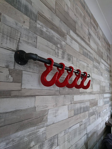 Retro industrial coat rack with red steampunk hooks on wood panel wall