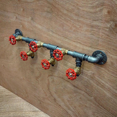 Industrial steampunk coat rack with red valve hooks on wooden wall