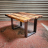 Industrial steampunk coffee table with wood block top and black metal legs on concrete floor