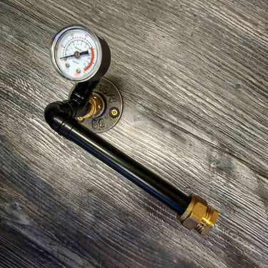 Steampunk pipe toilet paper holder with pressure gauge and brass fittings on wood background