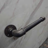 Industrial steampunk pipe toilet paper holder mounted on a marble wall
