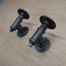 Pair of steampunk industrial pipe wall brackets on a wooden surface