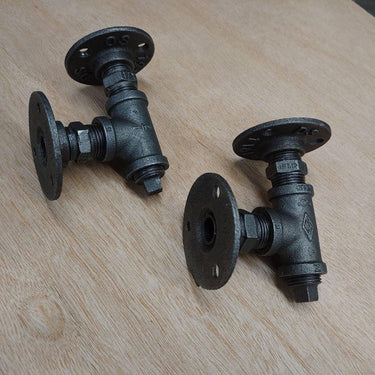Pair of industrial steampunk pipe wall brackets on wooden surface, black iron finish