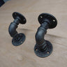 Pair of black steampunk pipe wall brackets on a wooden surface, industrial decor hardware