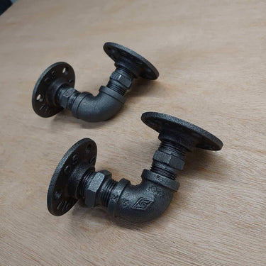 Pair of black steampunk industrial pipe wall brackets on wooden background