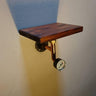 Steampunk wall shelf with dark wood plank, copper pipe, and industrial gauge on light wall