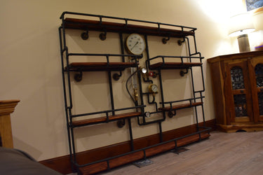 Steampunk shelving unit with industrial pipes, wood shelves, and vintage pressure gauges against a wall.