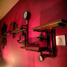 Industrial steampunk shelving unit with pipe fittings and pressure gauge on a red wall