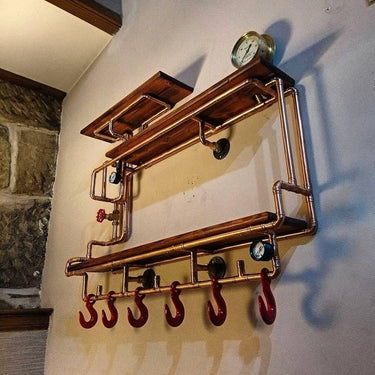 Steampunk industrial shelving unit with copper pipes, wood shelves, gauge, and red hooks mounted on wall