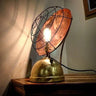 Industrial steampunk table lamp with exposed bulb, brass base, and copper reflector on wood surface