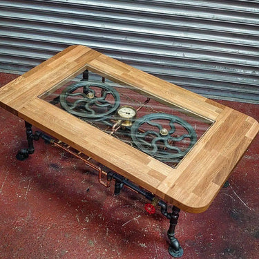 Steampunk coffee table with glass top, exposed gears, metal pipes, and wood frame