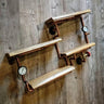 Steampunk industrial shelving unit with copper pipes, wood shelves, and gauge accents on wood wall.